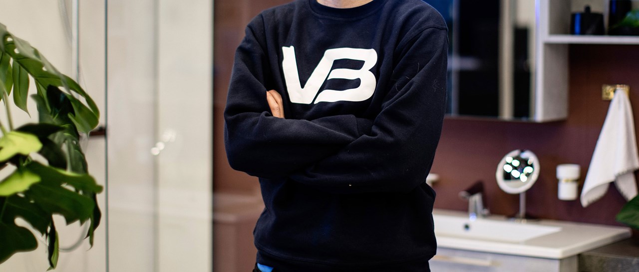 VB rørlegger med armene i kors. VB logo på mørkeblå genser.