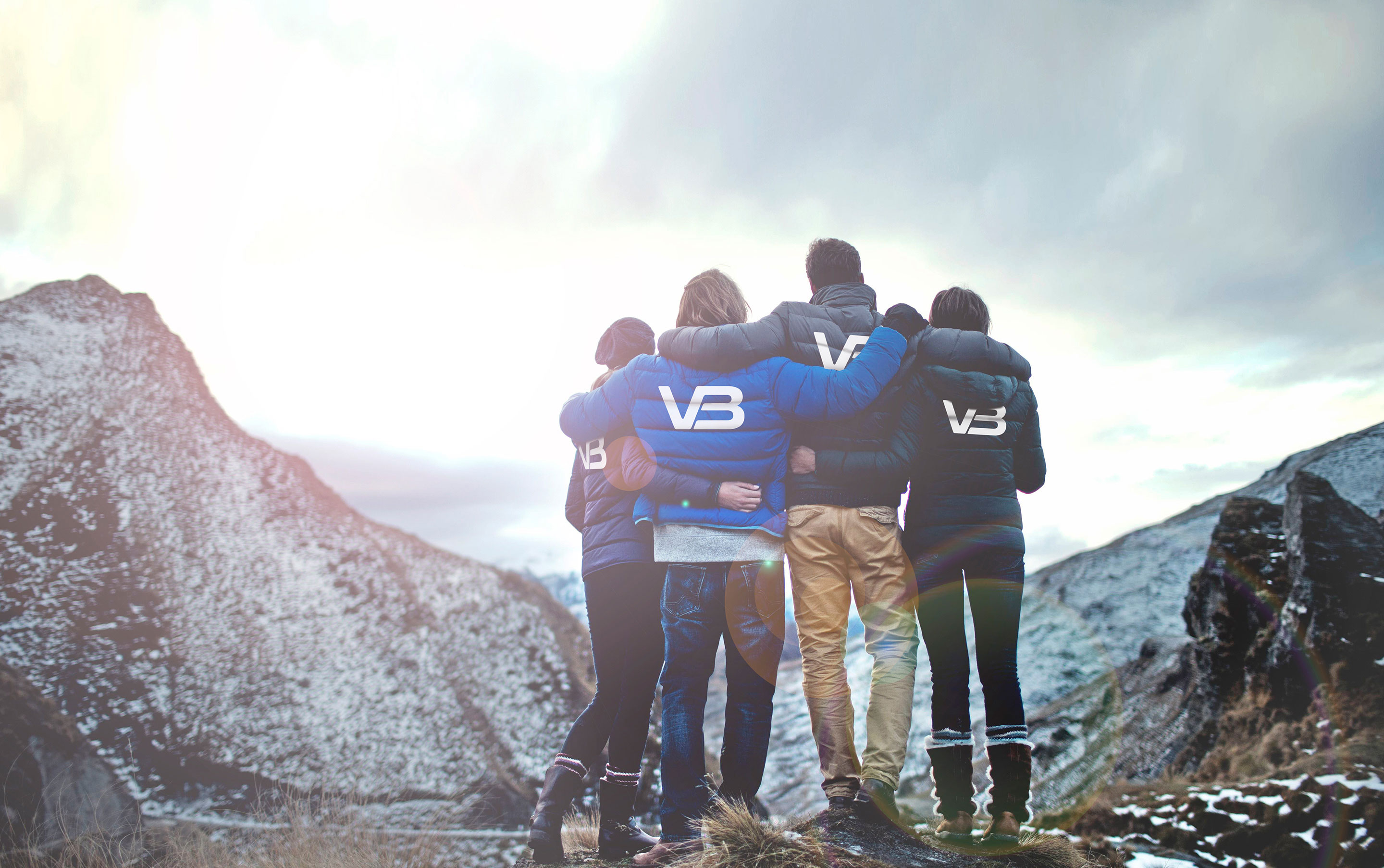 Fire VB medarbeidere ser ut mot fjell. Har på seg jakker med VB logo på baksiden.