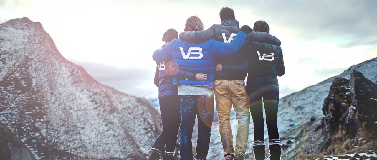 Fire VB medarbeidere ser ut mot fjell. Har på seg jakker med VB logo på baksiden.